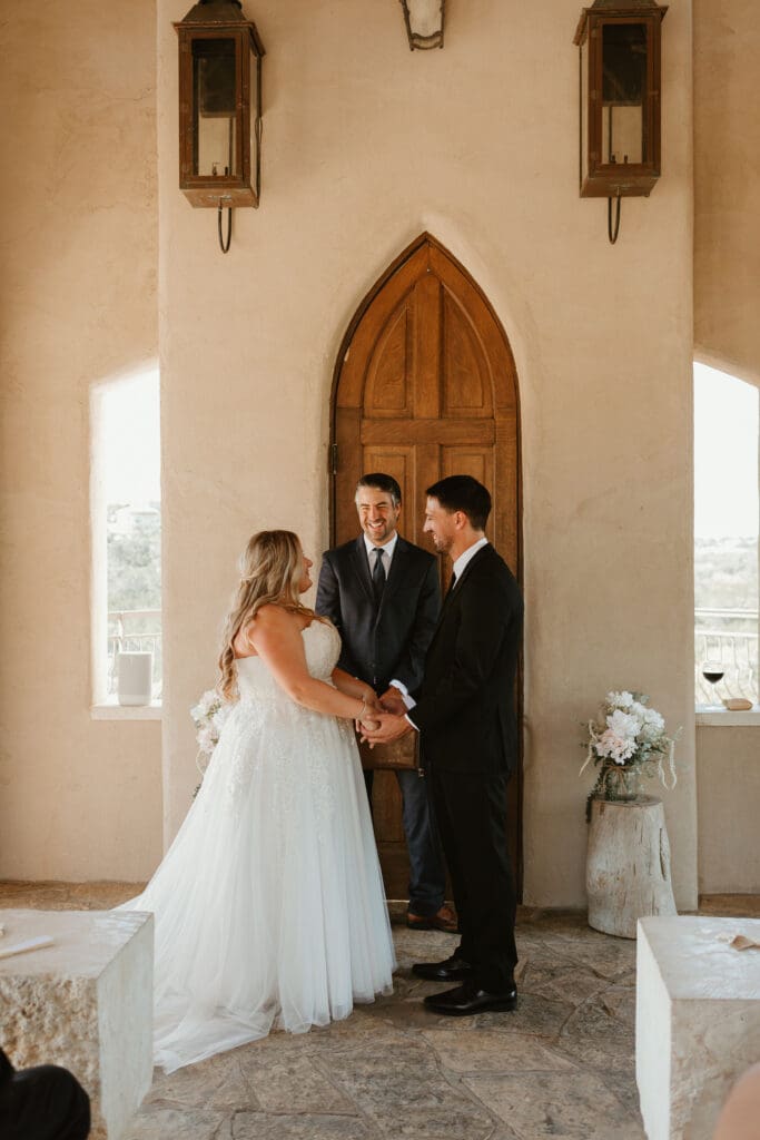 A couple having an intimate wedding ceremony at Chapel Dulcinea in Austin, Texas, on a sunny day, with clear skies and natural surroundings.