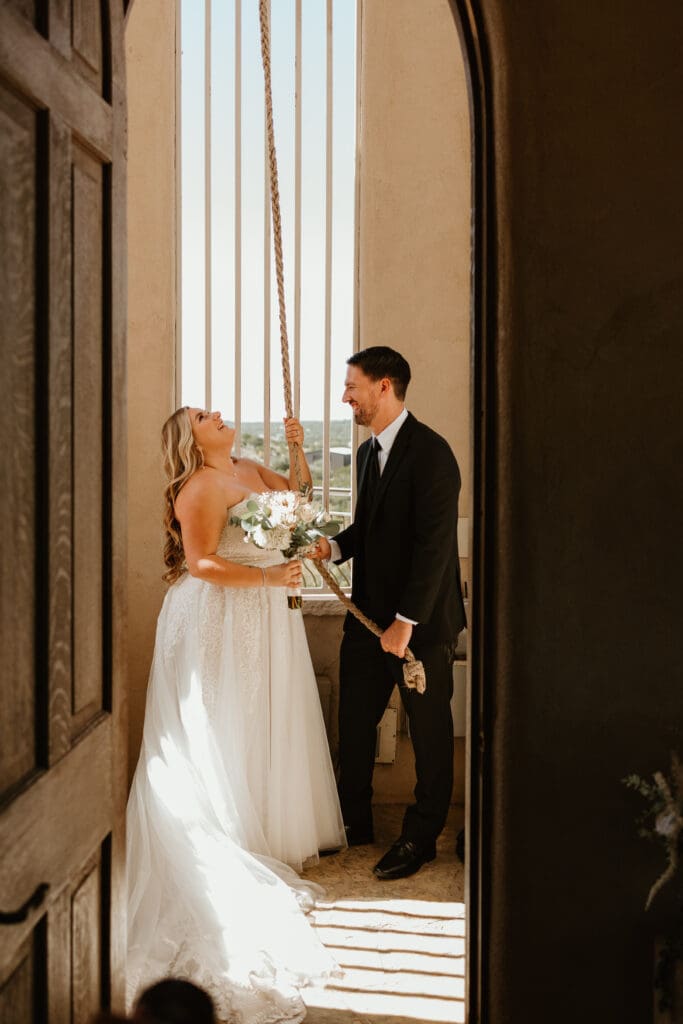 A couple ringing the wedding bells at Chapel Dulcinea in Austin, Texas, on a sunny day surrounded by friends and family.