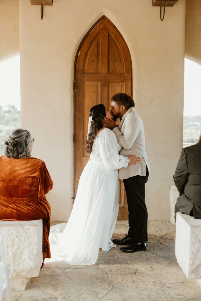 A couple having an intimate wedding ceremony at Chapel Dulcinea in Austin, Texas, on a sunny day, with clear skies and natural surroundings.