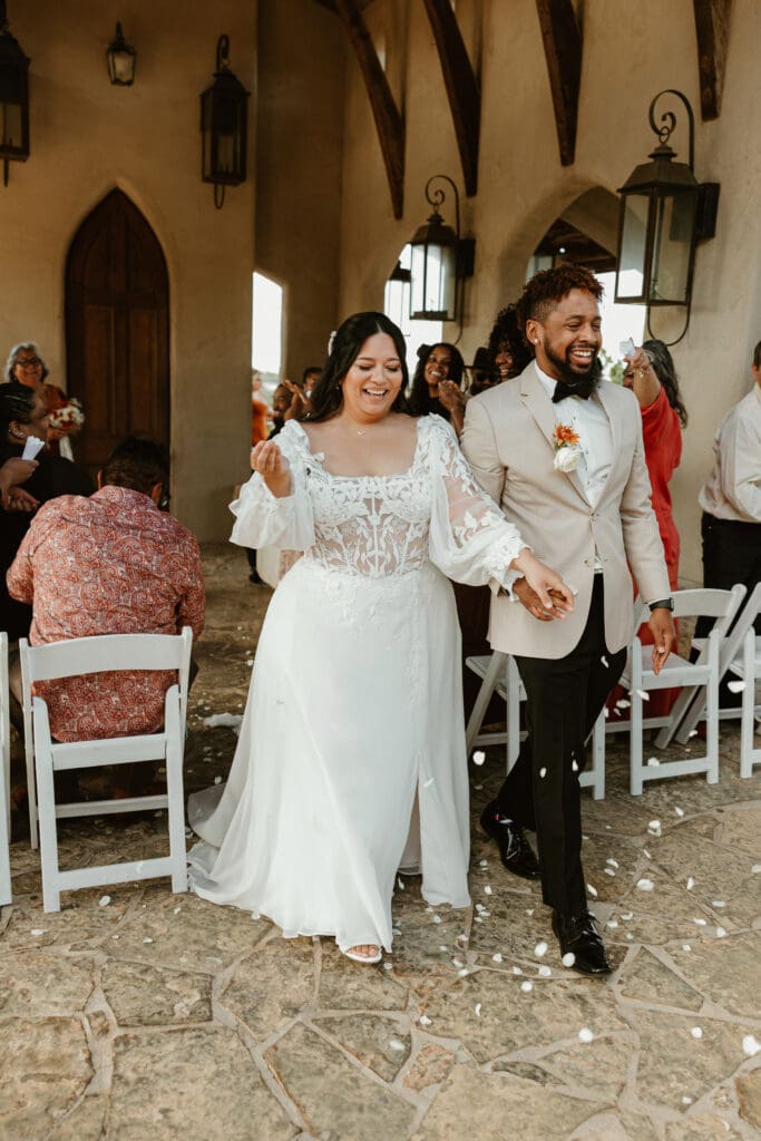 Newlyweds walk down the aisle together, smiling and celebrating their intimate wedding at Chapel Dulcinea in Austin, Texas.