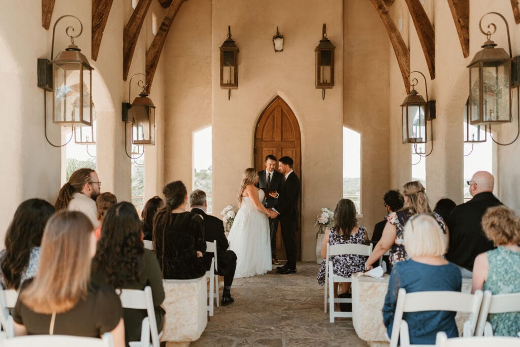 A couple having an intimate wedding ceremony at Chapel Dulcinea in Austin, Texas, on a sunny day, with clear skies and natural surroundings.