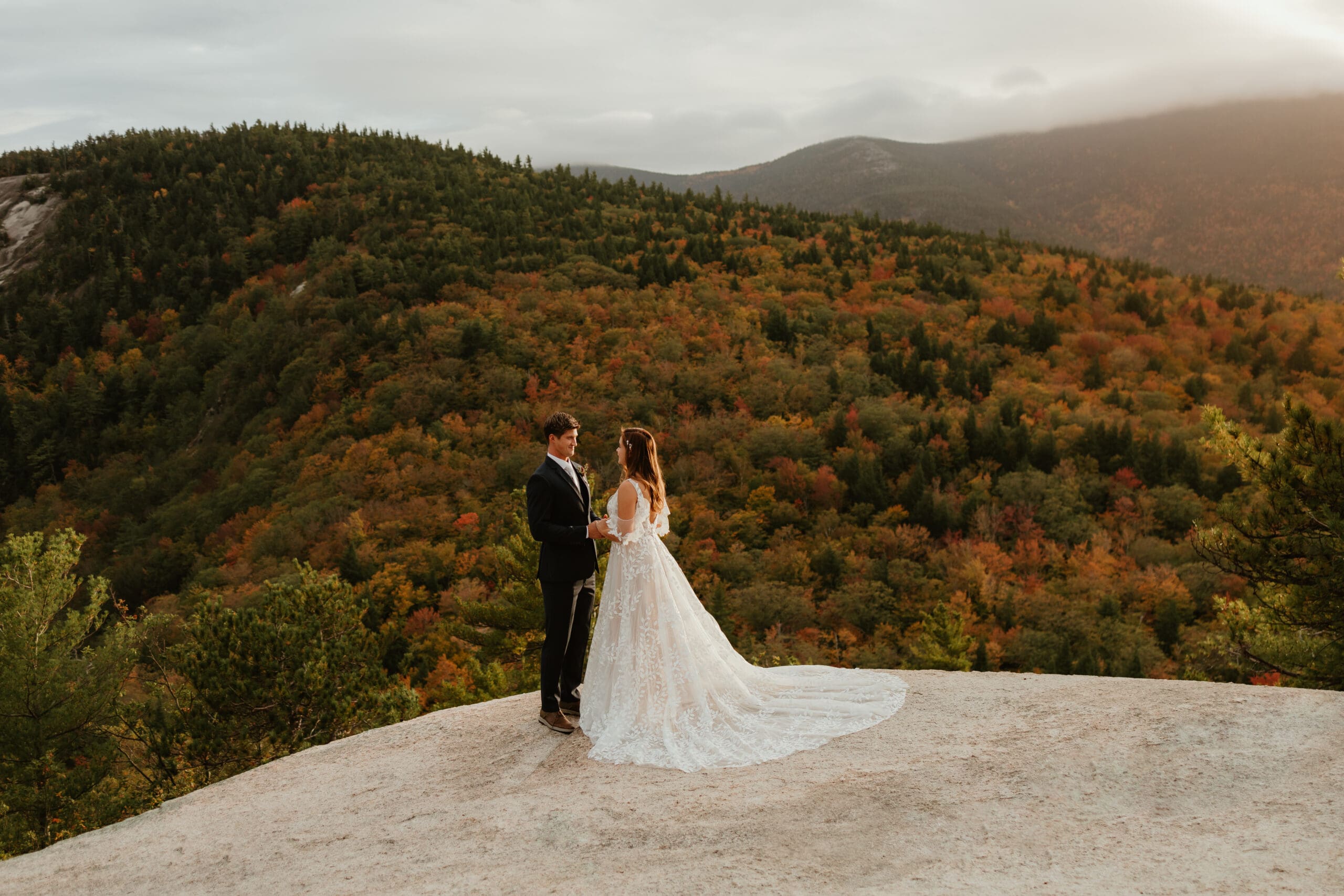 A couple eloping on a cloudy autumn evening in the mountains of New Hampshire, surrounded by colorful fall foliage.