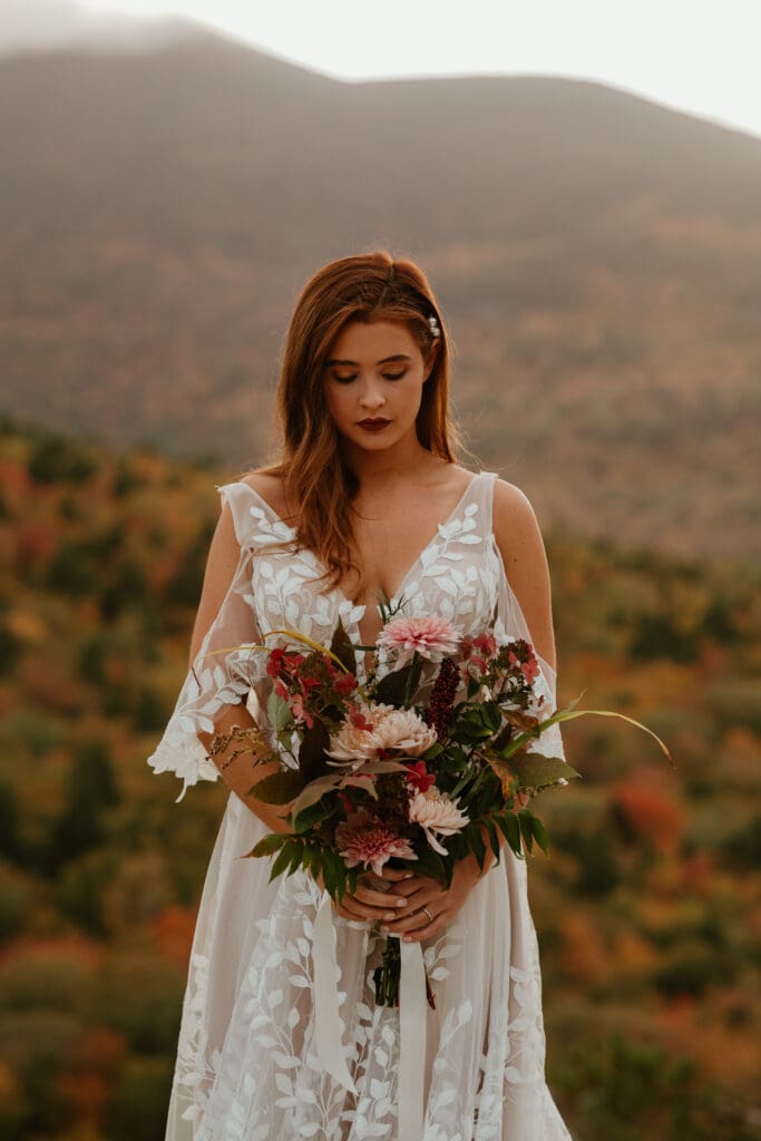 A couple eloping on a cloudy autumn evening in the mountains of New Hampshire, surrounded by colorful fall foliage.