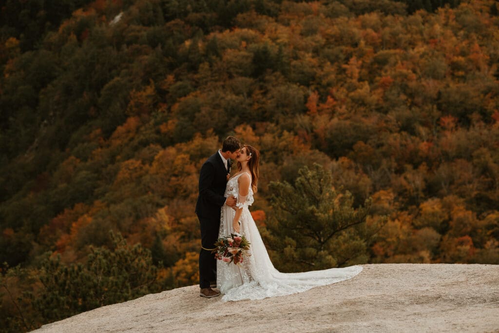 A couple eloping on a cloudy autumn evening in the mountains of New Hampshire, surrounded by colorful fall foliage.