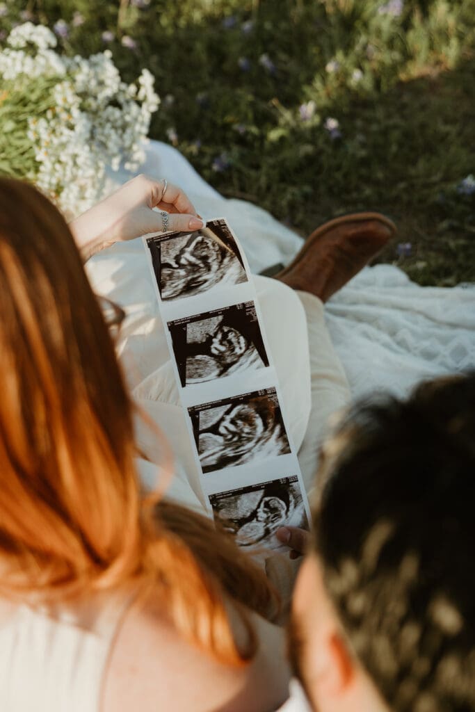 Expecting parents holding sonogram during a golden hour photo session in Cedar Park, Texas.
