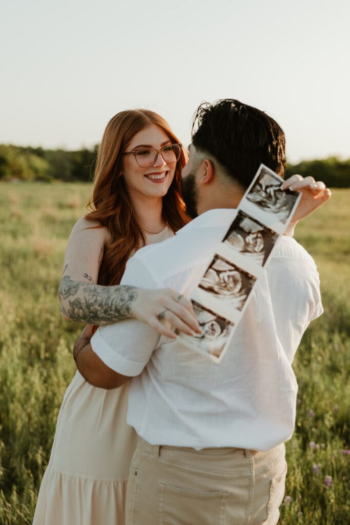 Expecting parents holding sonogram during a golden hour photo session in Cedar Park, Texas.