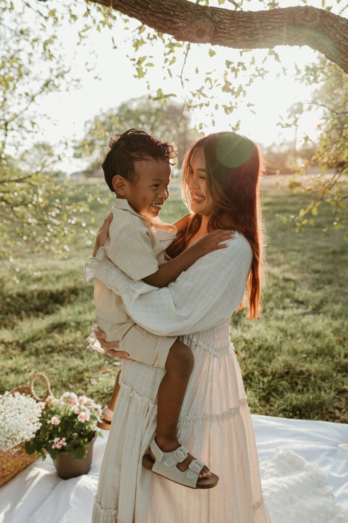 Mother and her three-year-old son smiling at each other during golden hour at Balcones District Park in North Austin.