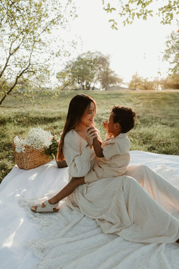 Mother gazing lovingly at her smiling son while they sit in a sun-drenched meadow at Balcones District Park.