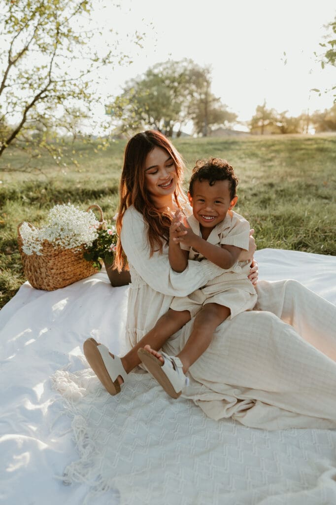 Mother and son sharing a laugh as they sit side by side in the golden hour light at a North Austin park.