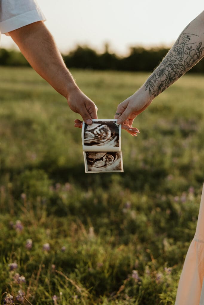 Close up of couple holding sonogram in a wildflower field in Central Texas. 