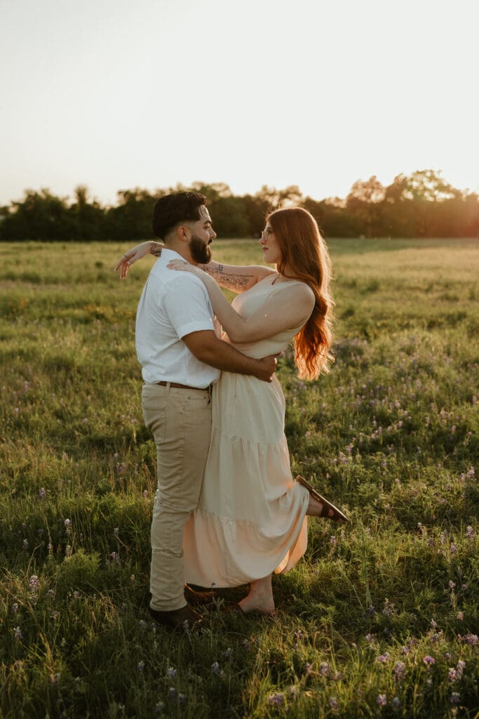 Couple holding each other in a wildflower field during golden hour in Cedar Park, Texas. 