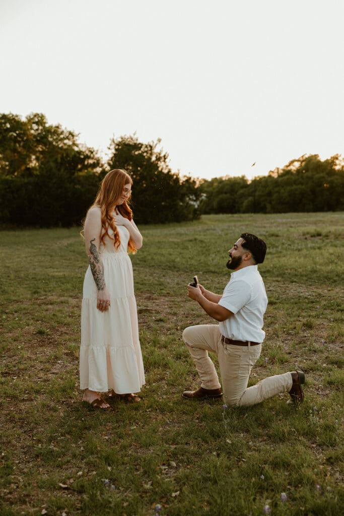 Emotional proposal moment captured at Brushy Creek Lake Park, surrounded by trees and setting sun.
