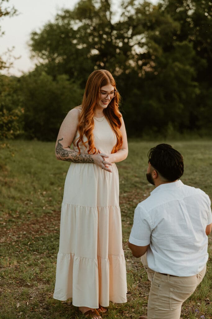 Pregnant woman smiling through tears as her boyfriend proposes during their announcement photo session.