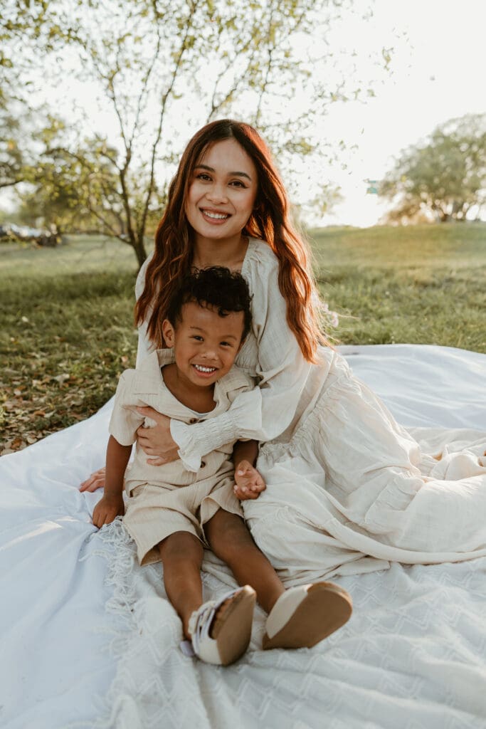 A joyful mom and her 3-year-old sharing a quiet, smiling moment as the sun sets behind them in North Austin.