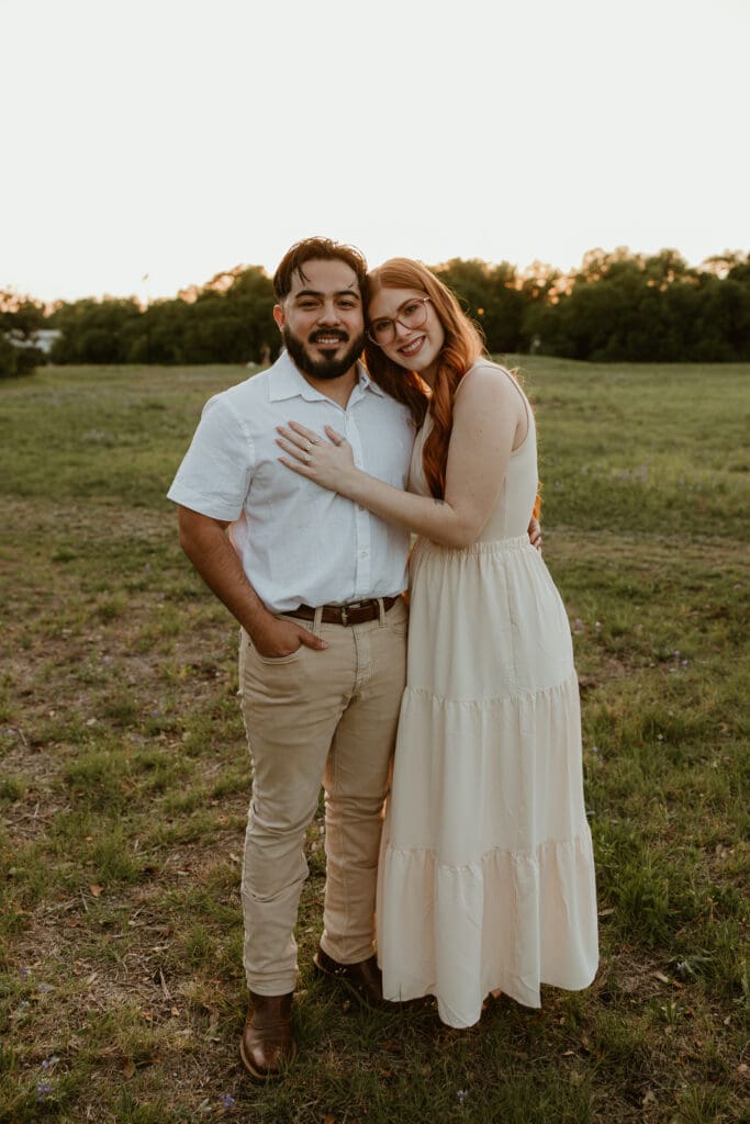 Couple smiling for the camera after surprise proposal success. 