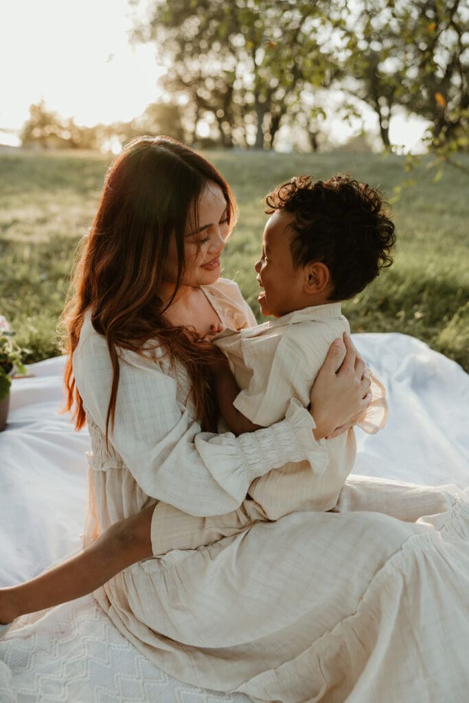 Mom and son embrace each other in cuddles during a beautiful golden hour at Balcones District Park in North Austin,