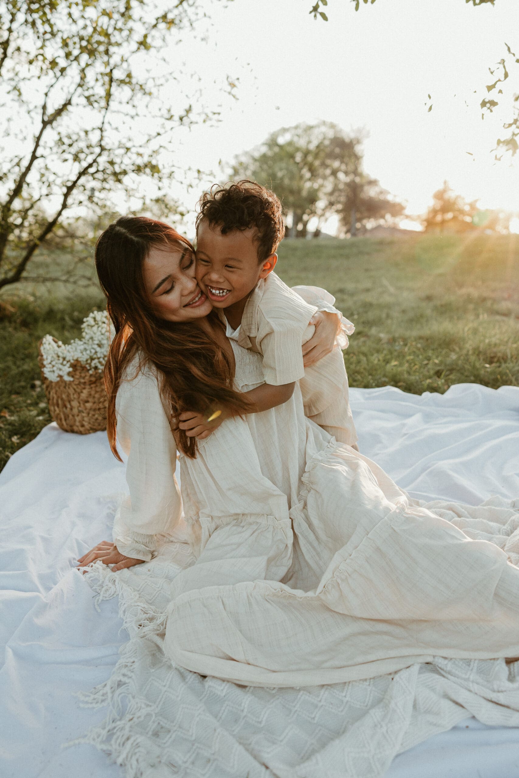 Mom and young son snuggling in a golden hour field at Balcones District Park in Austin, Texas.