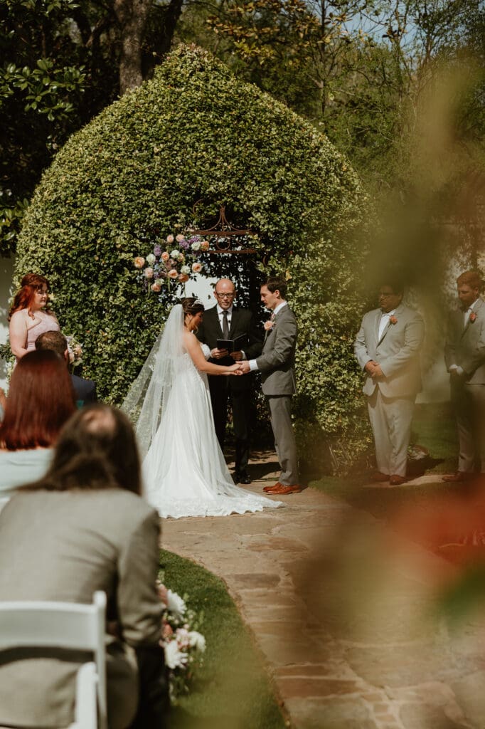 Bride and groom exchanging vows midday at The Hummingbird House garden venue near Austin