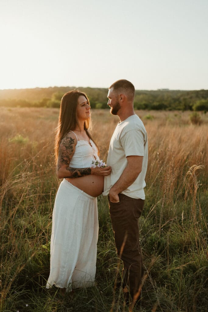 Expecting parents hold hands in open field during golden hour at Common Fords Ranch in Austin. 
