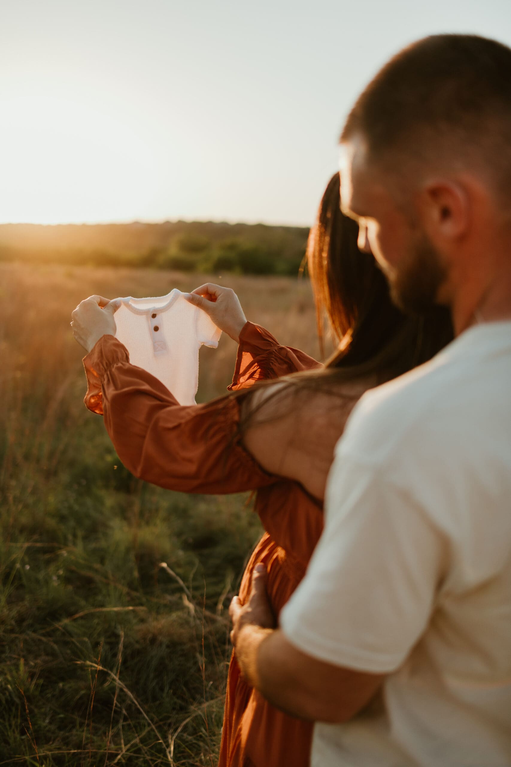 Mom and dad holding newborn shirt during golden hour photo session in Austin Texas
