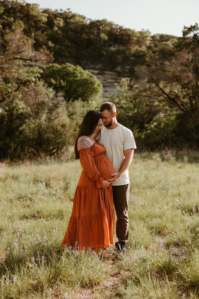 Expecting parents hold baby bump during golden hour photoshoot in Austin. 