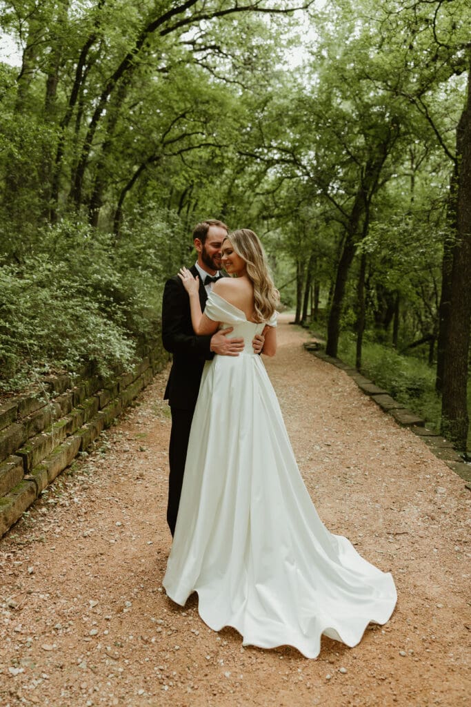 Bride and groom embracing each other in lush pathway during Spring in Austin Texas