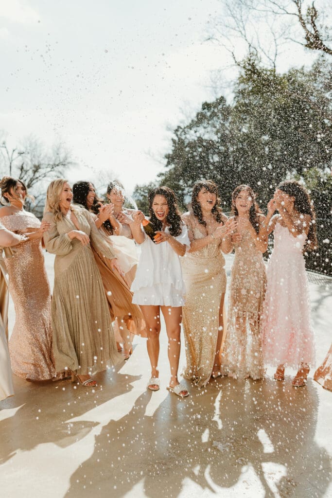 Bride and bridesmaids pop champagne on wedding day in Austin, Texas.