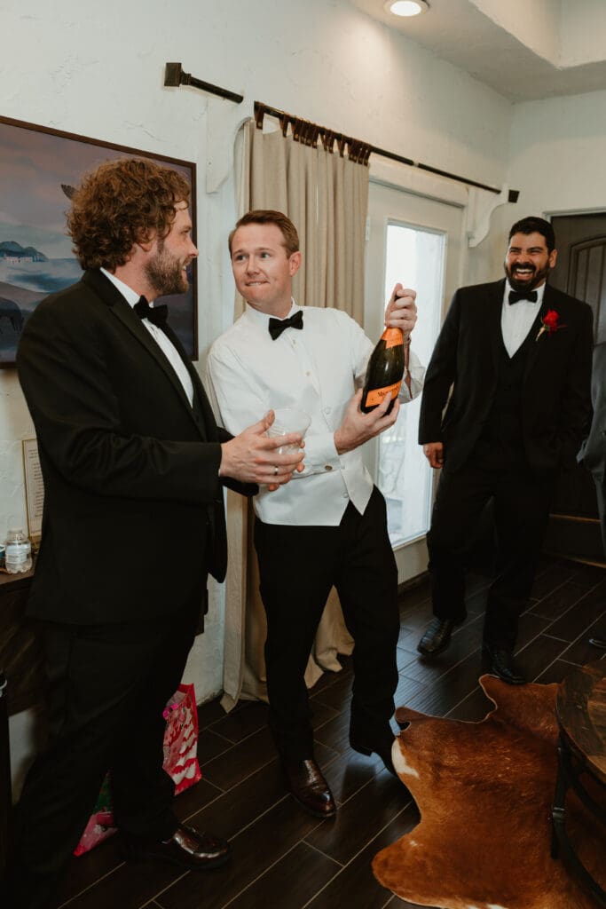 Groom popping champagne with groomsmen on wedding day in Austin, Texas.