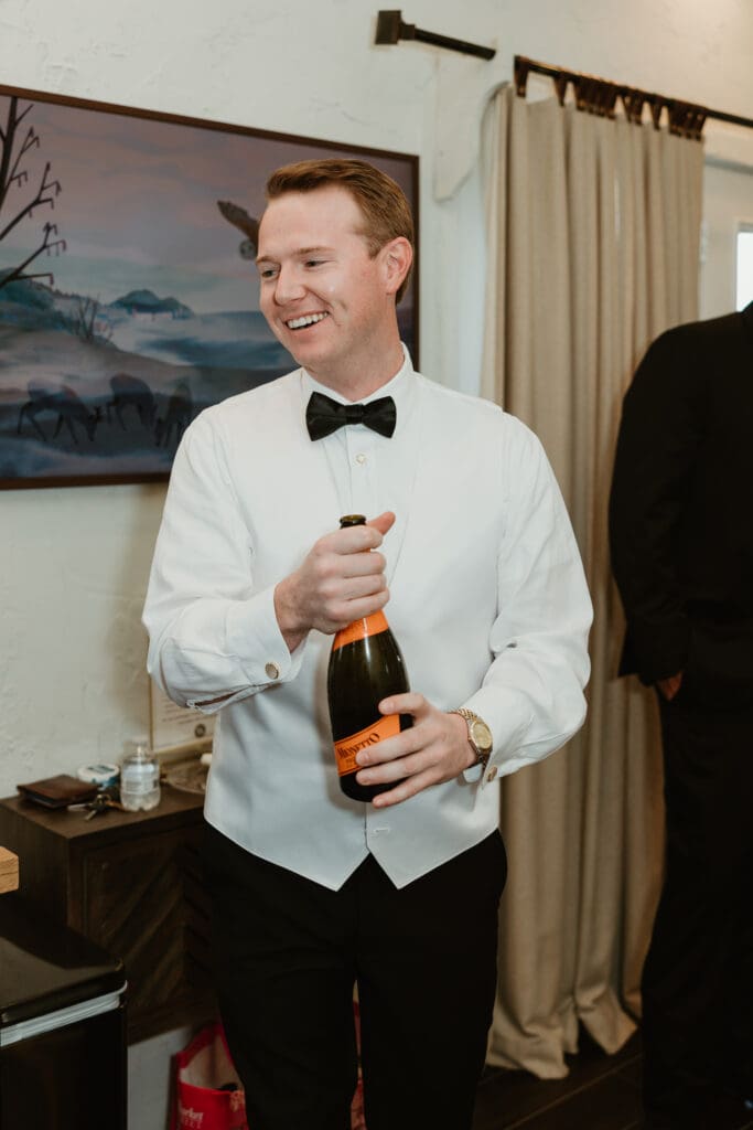 Groom popping champagne with groomsmen on wedding day in Austin, Texas.