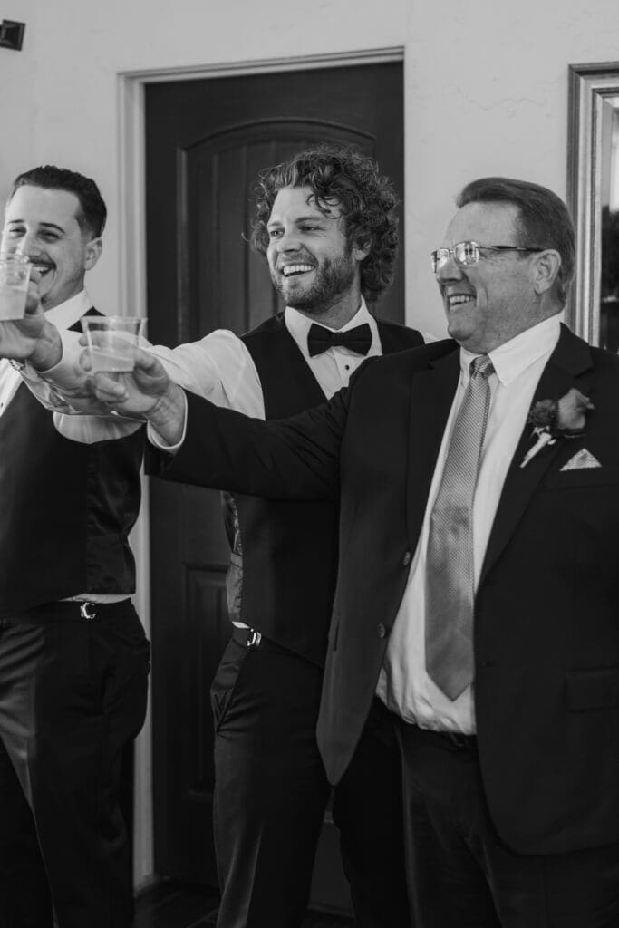 Groom popping champagne with groomsmen on wedding day in Austin, Texas.