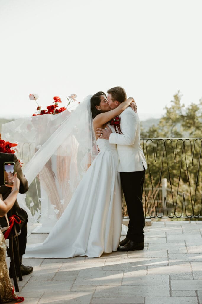 Bride and groom exchanging a kiss on the outdoor terrace at Villa Antonia.

