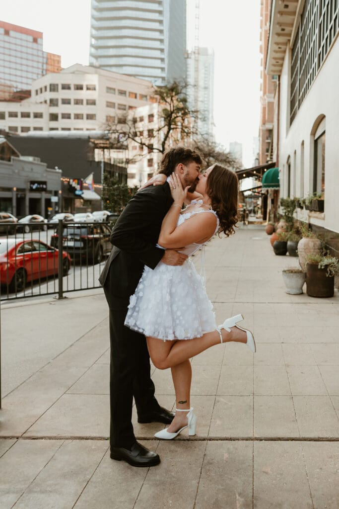 Engaged couple share a kiss outside of downtown Austin bar