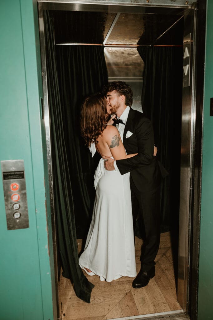 Engaged couple share a cheeky kiss in elevator in downtown Austin bar.