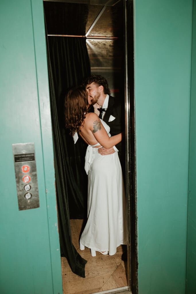 Engaged couple share a cheeky kiss in elevator in downtown Austin bar.