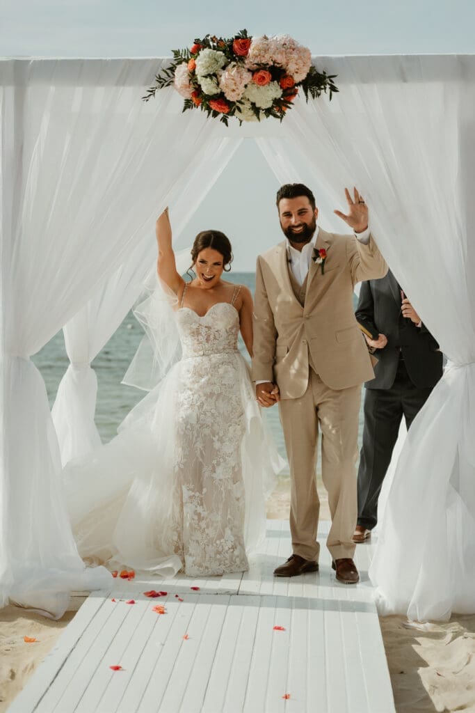 Bride and groom celebrate walking down the aisle on Cape Cod beach, captured by New England wedding photographer.